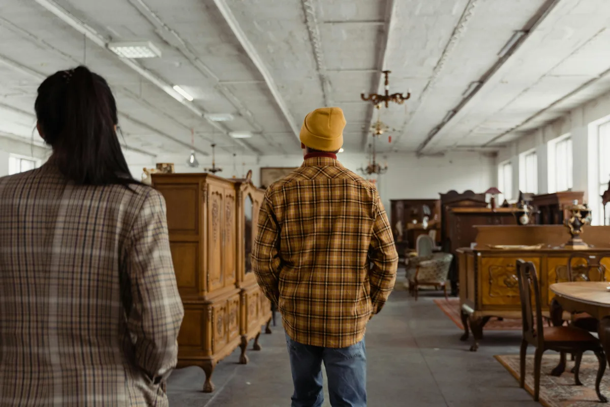People browsing wooden cabinets and furniture in a bright interior